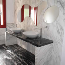 Rivestimento in marmo Calacatta oro con specchio intarsiato e piano in Nero Portoro.